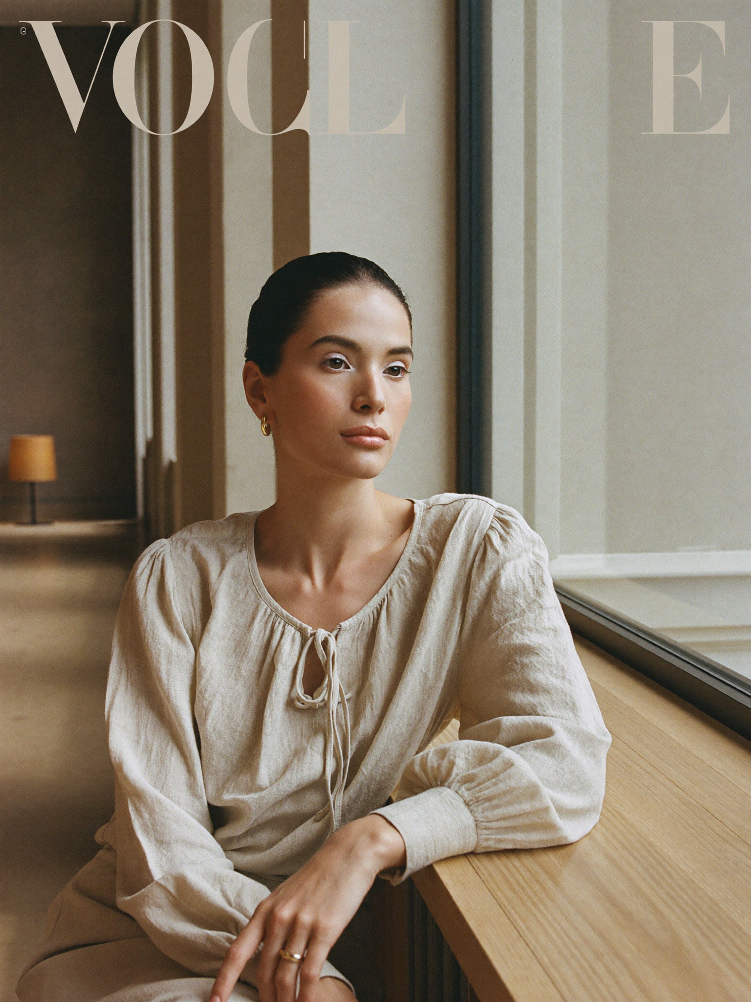 Arlisse editorial, woman seated by a window in an oatmeal linen blouse